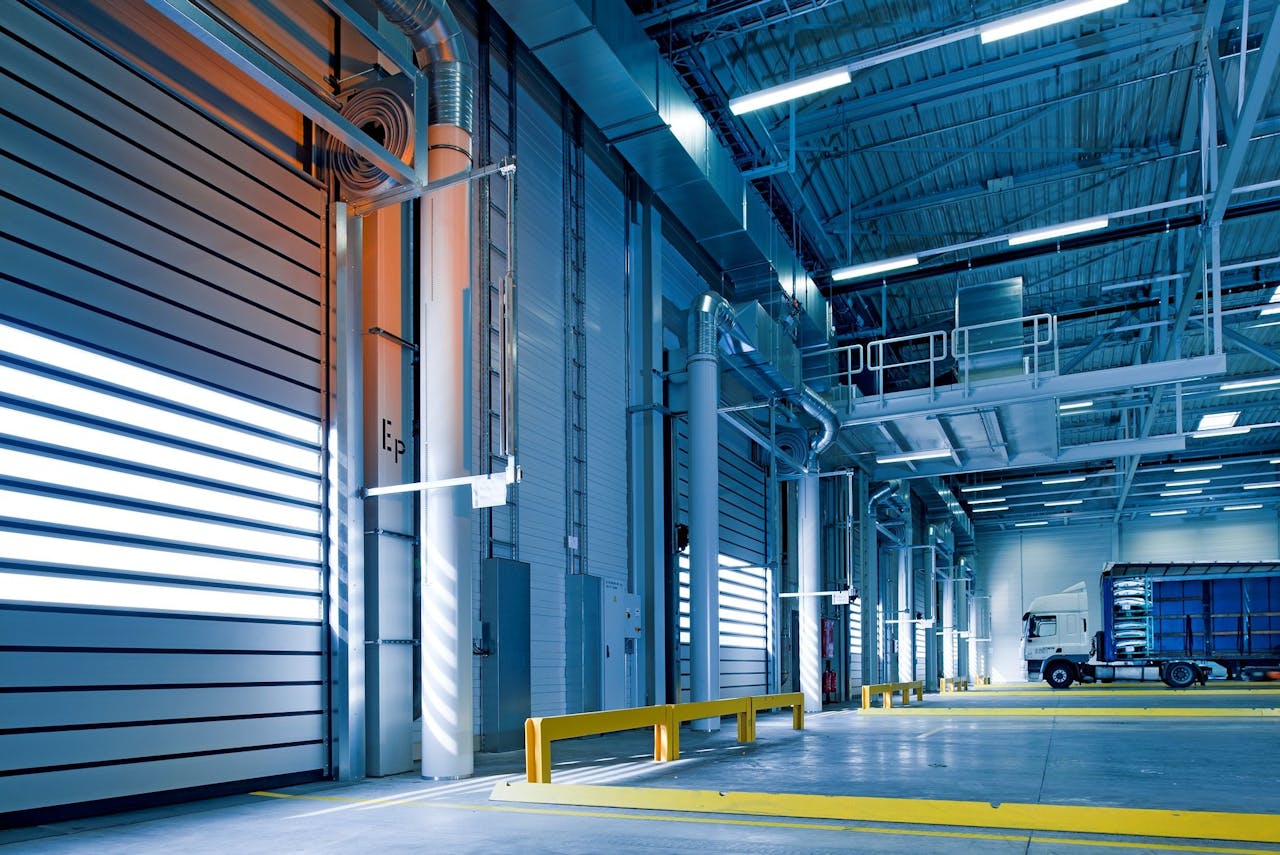 heros-img Spacious and modern warehouse interior with parked truck and steel structures.
