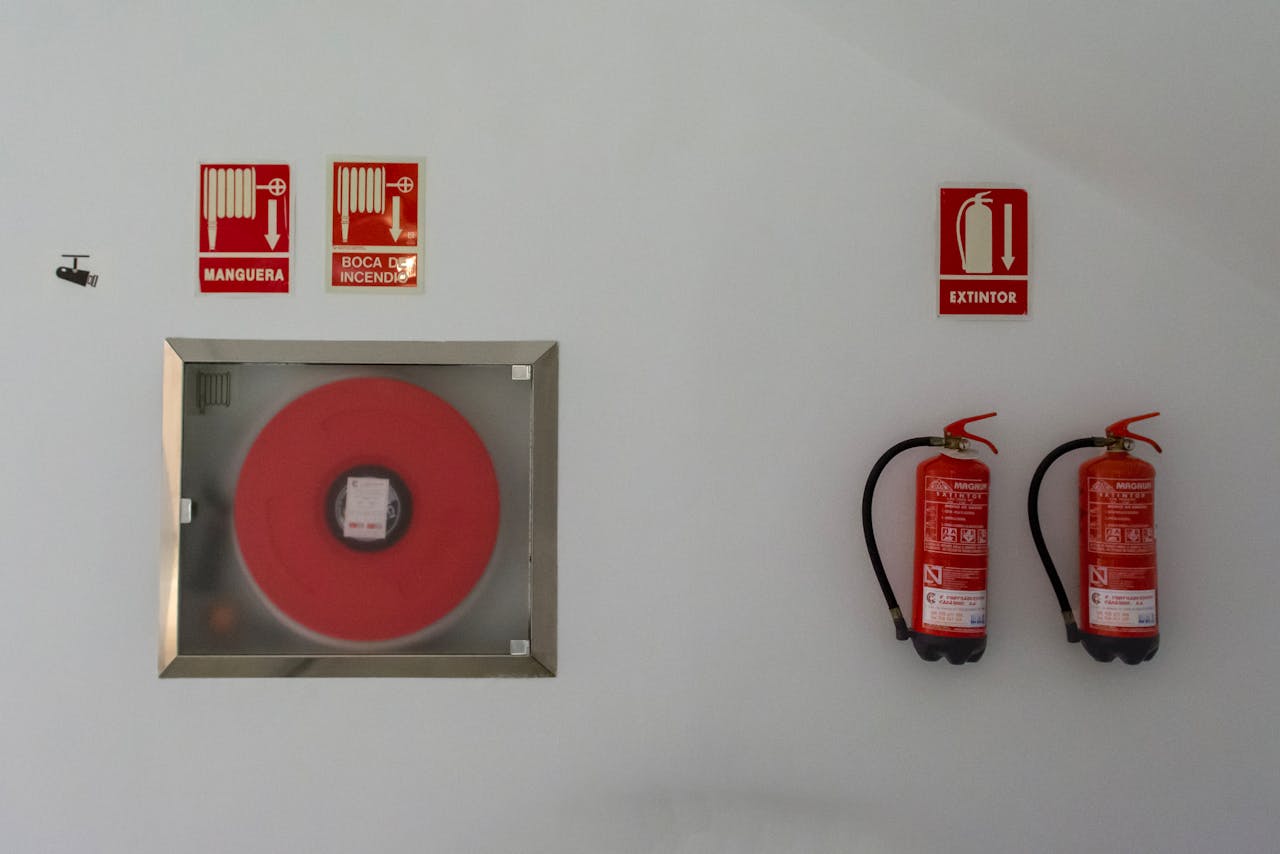 services-04 Fire safety setup with extinguishers and hose reel on a white wall for emergency preparedness.